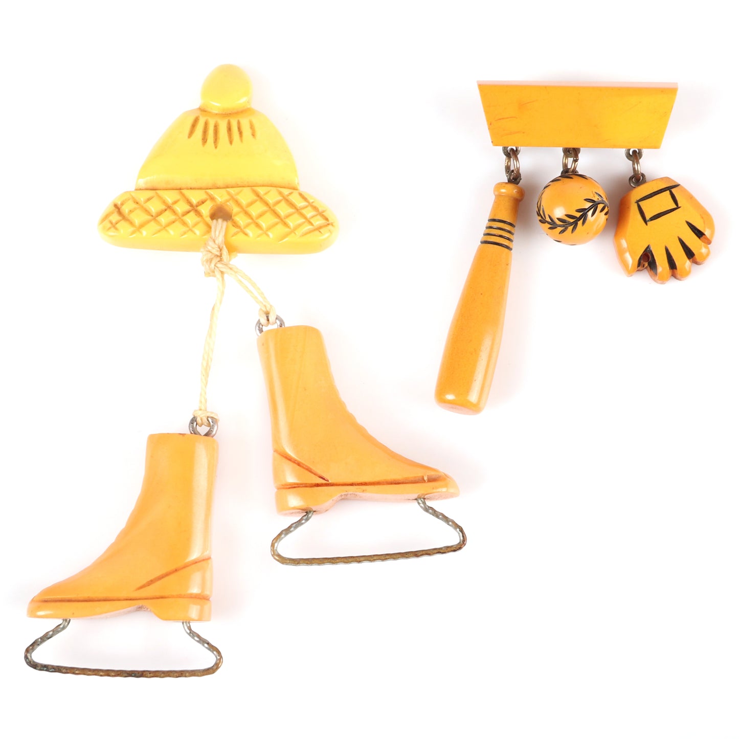 Vintage Bakelite 2pc. sports theme dangle charm pins. Carved butterscotch ice skates and cap, and baseball, bat and glove charms on bar pin. 4 1/4" H x 2 1/2" W (one)