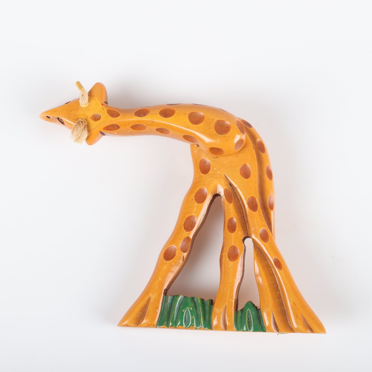 Vintage Bakelite carved figural articulated Giraffe pin brooch. Neck swivels 360 degrees. Painted grass. Wear to wax coating on strings. 4 12" H x 2 1/2"W