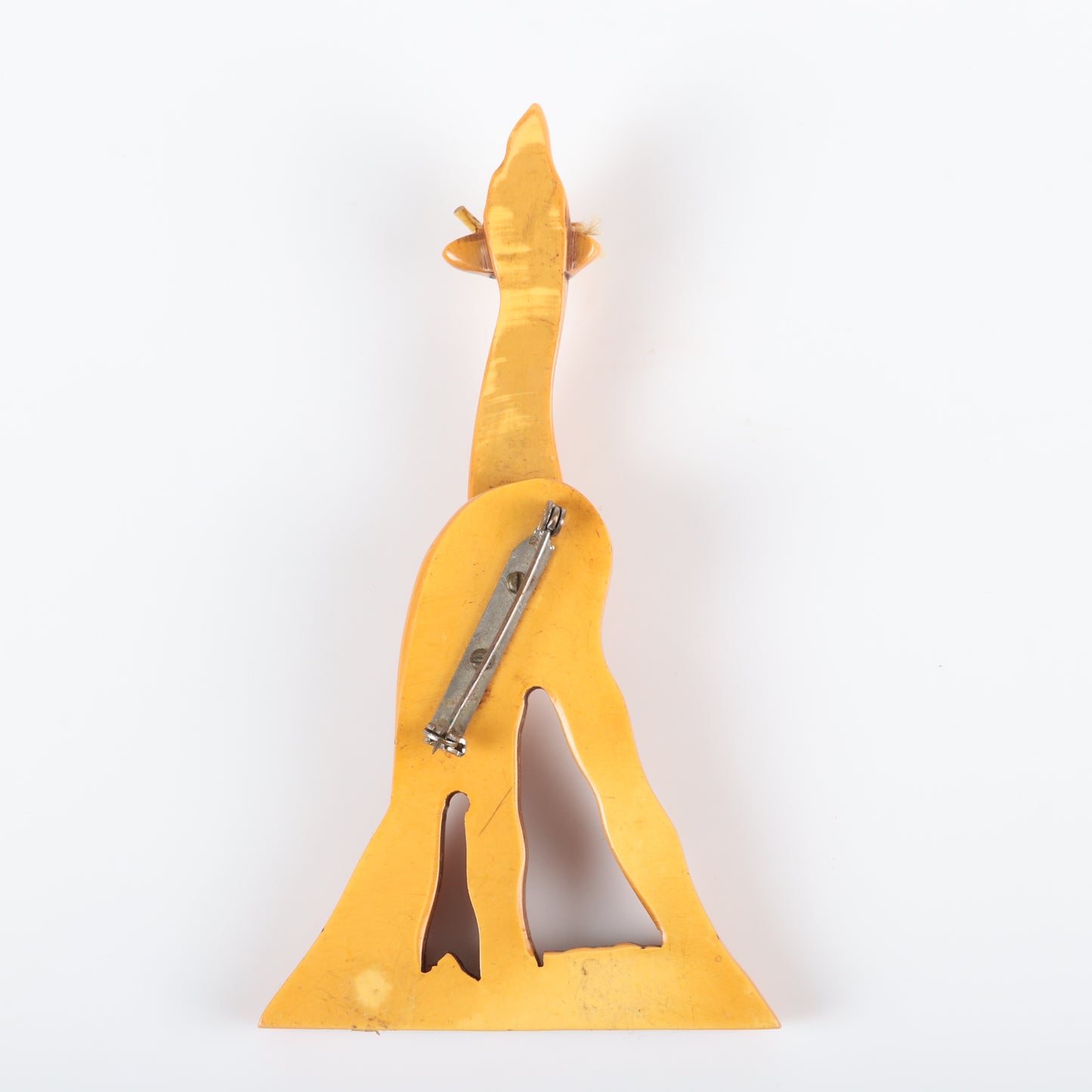 Vintage Bakelite carved figural articulated Giraffe pin brooch. Neck swivels 360 degrees. Painted grass. Wear to wax coating on strings. 4 12" H x 2 1/2"W