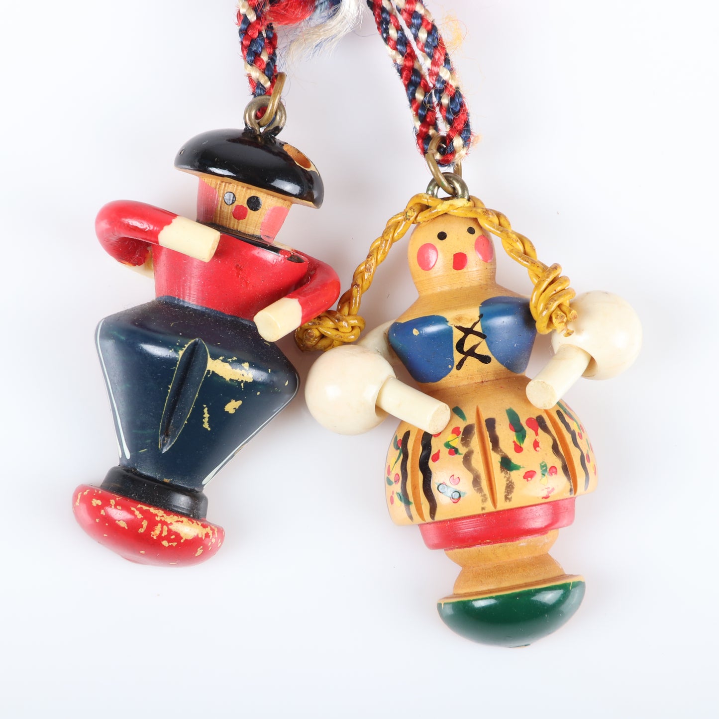 Vintage Bakelite Martha Sleeper bar pin with dangling painted carved German figures. Celluloid arms, waxed string braids, and braided floss bow. Man is missing a plume piece from his cap. 3 1/2" H x 2 1/2" W