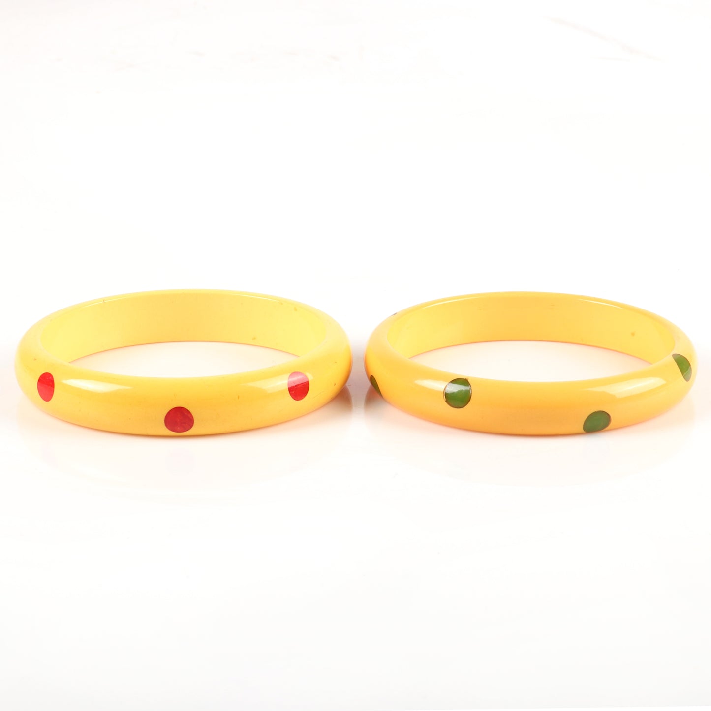 Vintage Bakelite 2pc. laminated dot bangle bracelets in cream corn each with 8 marbled red and green hi-low polka dots. 2 1/2" inner diam., 1/2" W