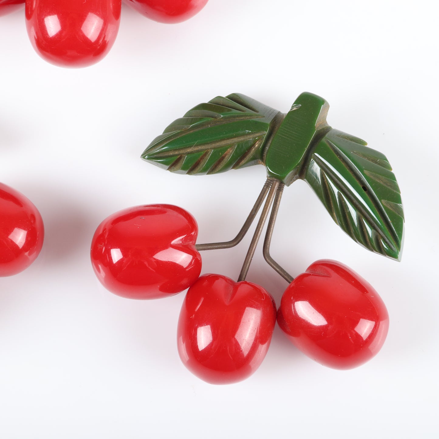 Vintage Bakelite set of 3 unusual cherry fruit pins. Each featuring 3 carved red cherries suspended with metal wire from carved green bakelite leaves. 2 1/4" H x 2 1/2" W
