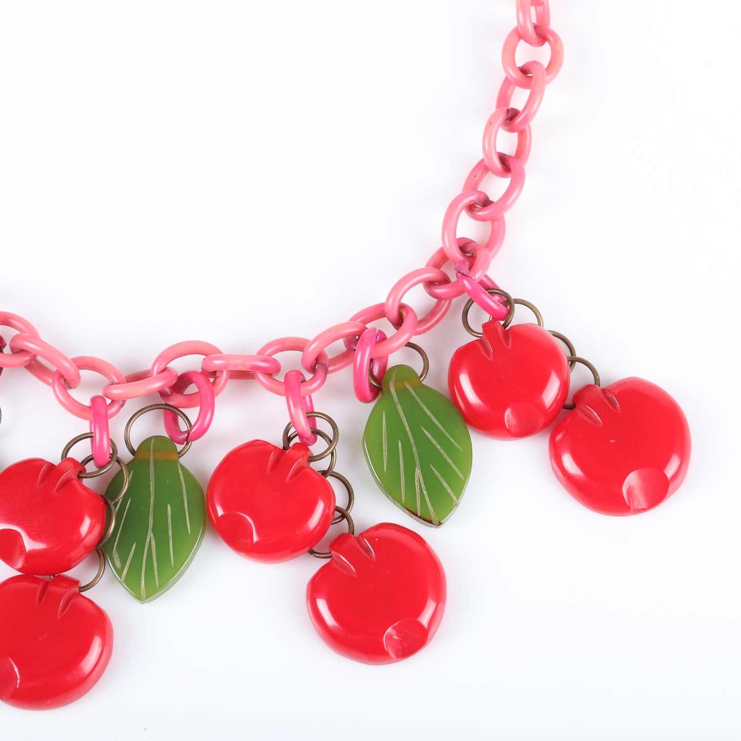 Vintage Bakelite Carmen Miranda red flat Cherry fruit charm necklace with dangling carved flat fruit charms on pink over-dyed celluloid chain with green bakelite leaves. 17 1/2" L