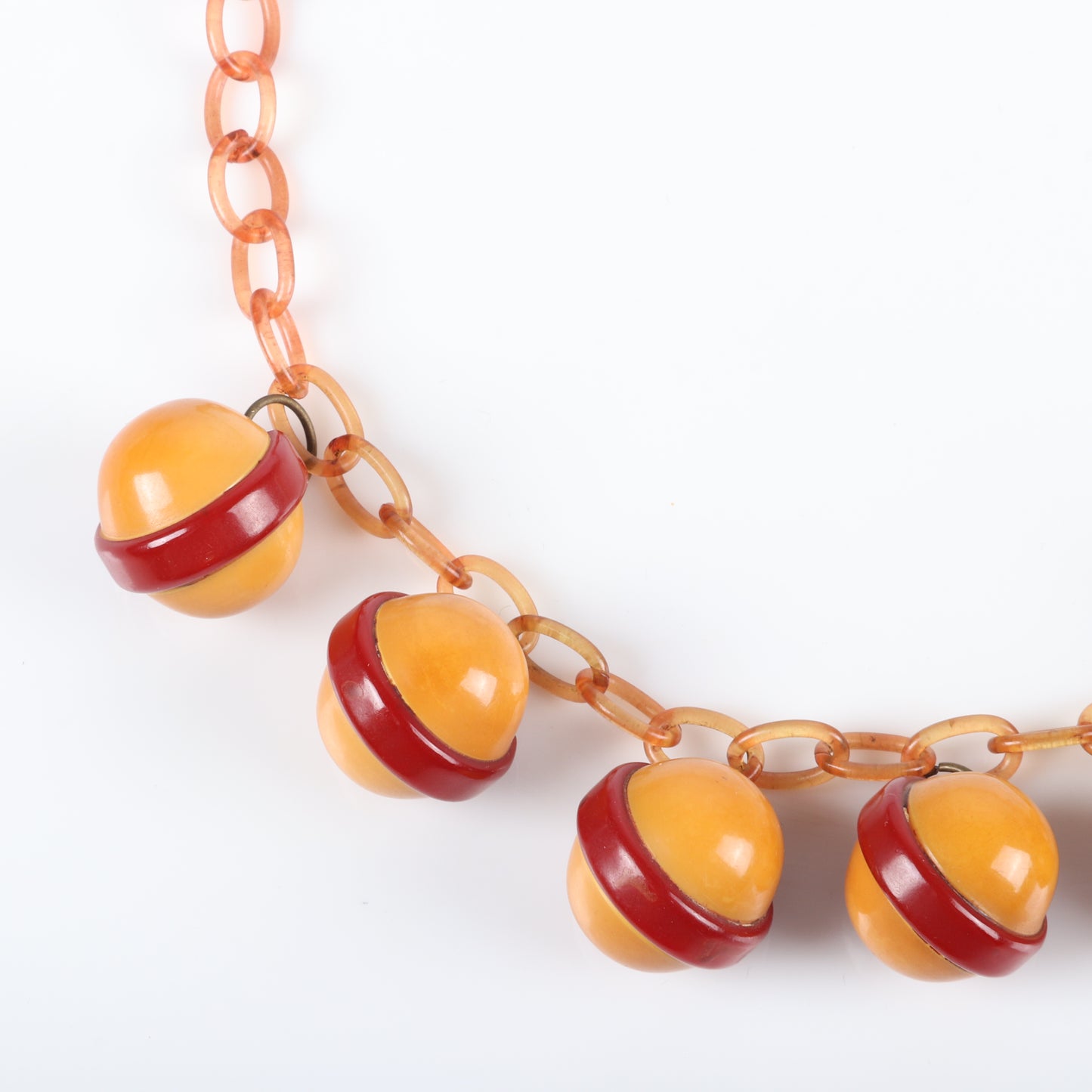 Vintage Bakelite Saturn ball charm necklace features 8 laminated sandwiched red and butterscotch dangles on apple juice celluloid chain. 17 1/2" L