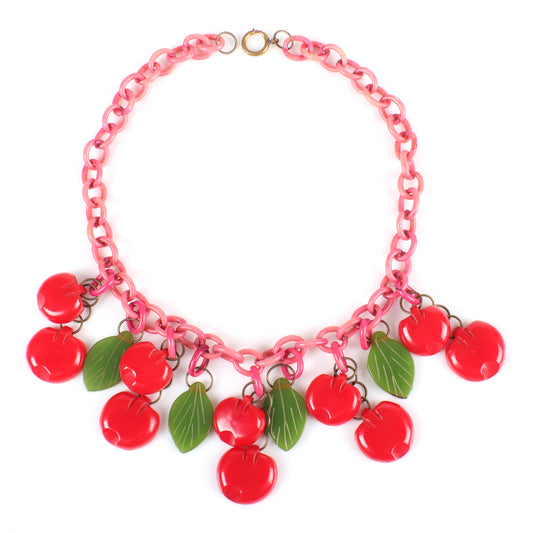 Vintage Bakelite Carmen Miranda red flat Cherry fruit charm necklace with dangling carved flat fruit charms on pink over-dyed celluloid chain with green bakelite leaves. 17 1/2" L