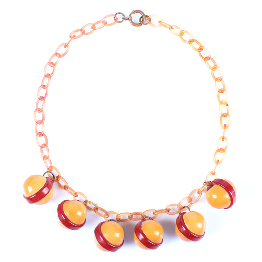 Vintage Bakelite Saturn ball charm necklace features 8 laminated sandwiched red and butterscotch dangles on apple juice celluloid chain. 17 1/2" L