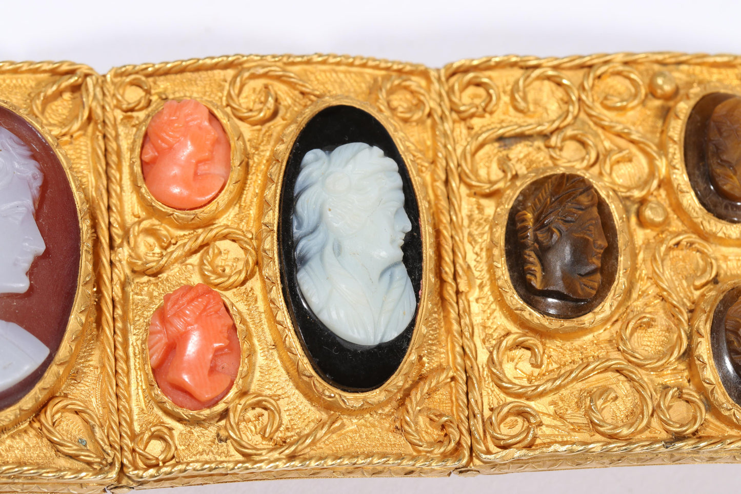 Antique 18K yellow gold Victorian panel bracelet with 19 intricate left and right facing cameos carved from natural stone including tigers eye, onyx, coral, shell, and more. 8 1/4"L x 1 1/8"W